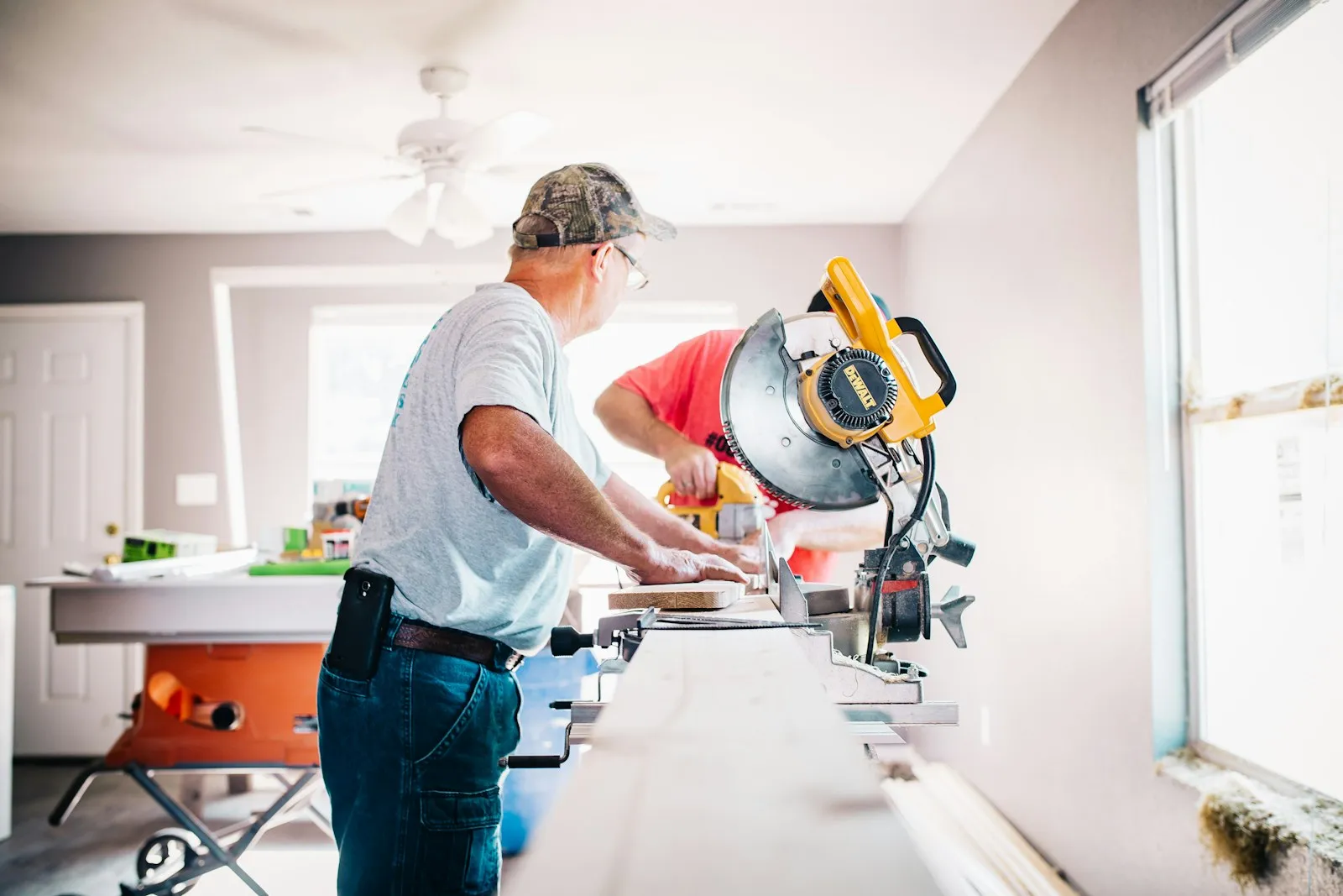 A contractor cutting trim on a miter saw inside a house under renovation